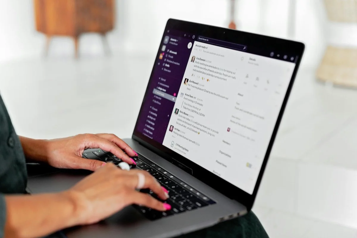 Donna che digita su laptop usando un'app di messaggistica in ufficio moderno