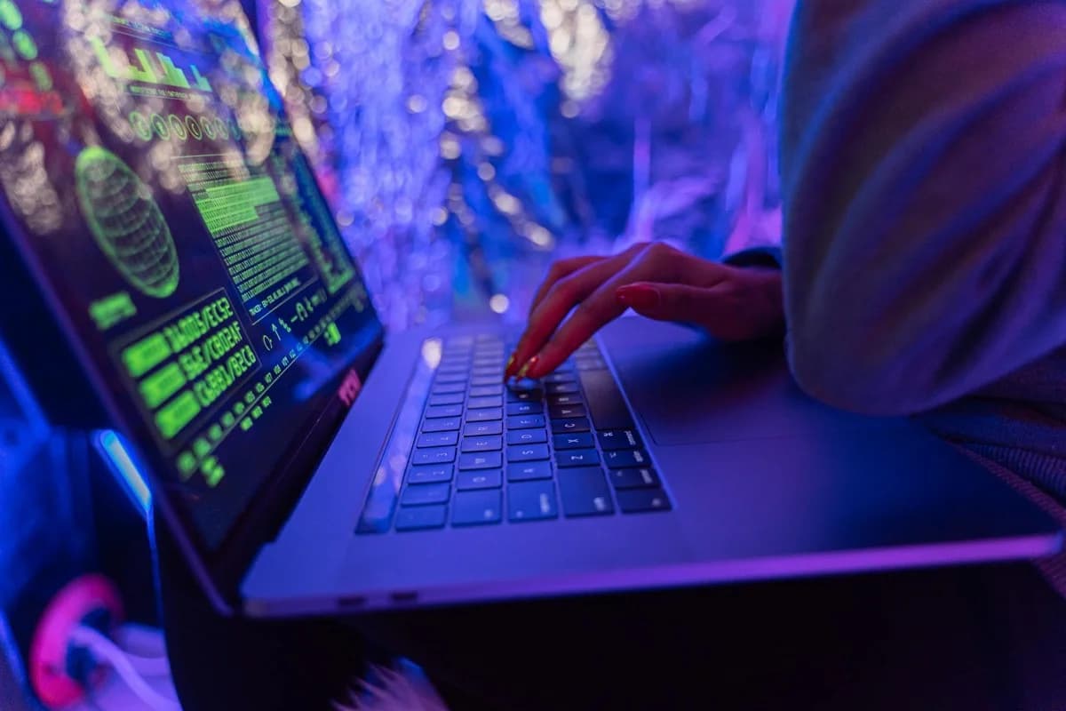 Mani che digitano su laptop con grafica di cybersecurity, tema compliance digitale