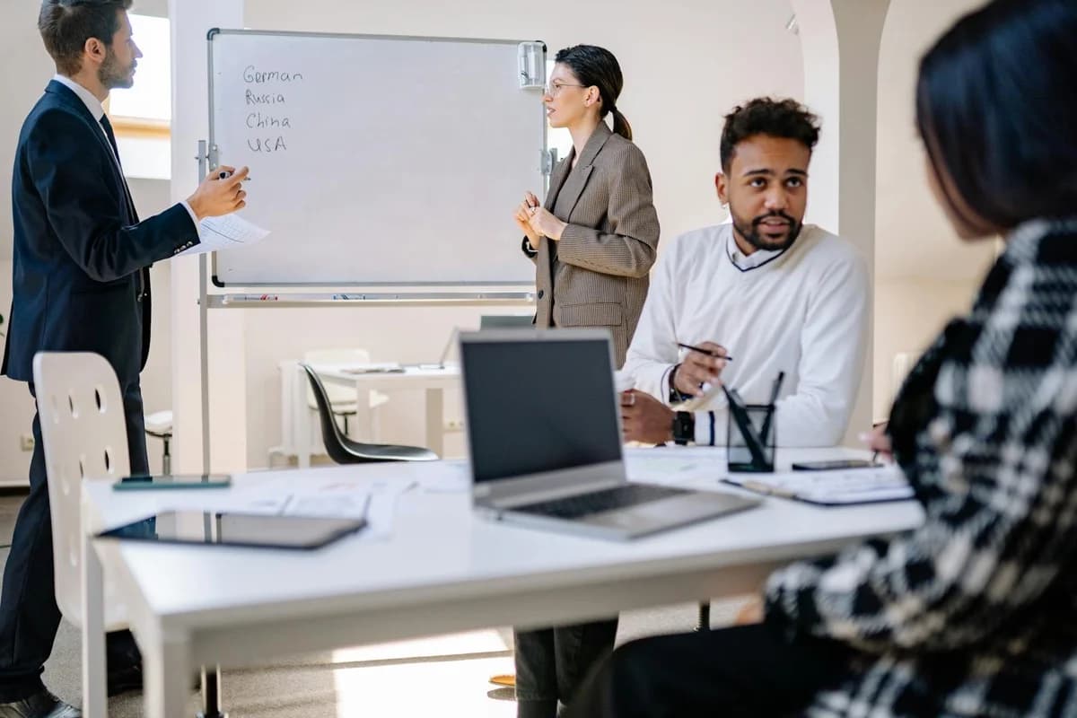 Team diversificato collabora in ufficio su strategia business con laptop e documenti